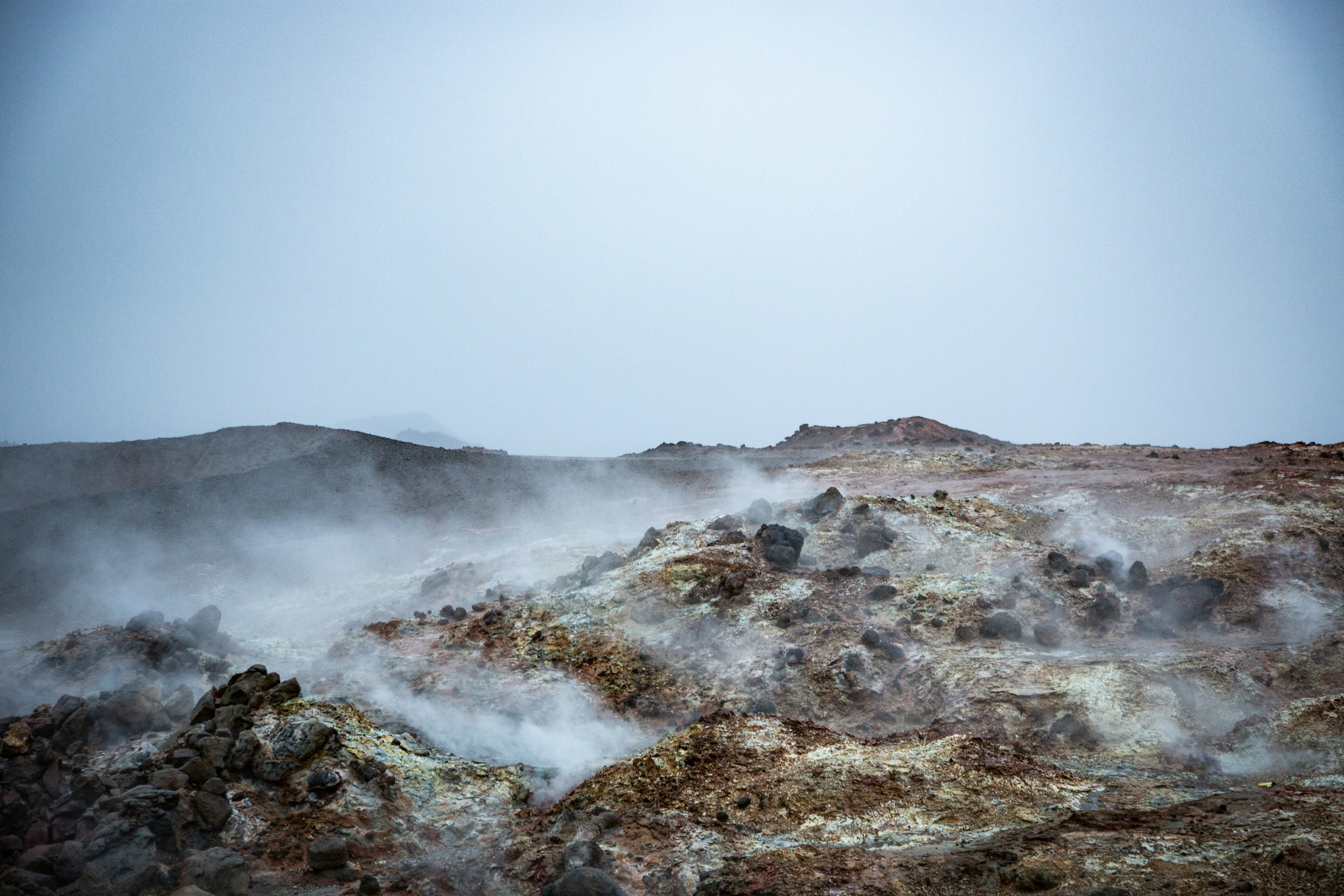 Steam rising from rocky geothermal ground in Iceland.